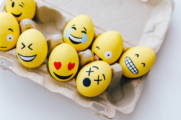 Yellow painted eggs in an egg box with various facial expressions